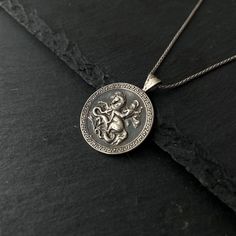 Saint George was a Christian who is accepted as a saint in Christianity. According to traditional rumors, he was a soldier in the Roman army. This silver coin necklace tells the story of St.George and the dragon. Diameter 25 mm Story The tradition tells that a fierce dragon was causing panic at the city of Silene at the time George arrived there. In order to prevent the dragon from devastating people from the city, they gave two sheep each day to the dragon, but when the sheep were not enough they were forced to sacrifice humans instead of the two sheep. The human to be sacrificed was elected by the city's own people and one time the king's daughter was chosen to be sacrificed but no one was willing to take her place. George saved the girl by slaying the dragon with a lance. The king was s Symbolic Silver Coin Necklace, Silver Engraved Symbolic Coin Necklace, Silver Symbolic Coin Necklaces, Silver Coin Necklaces With Symbolic Style, Silver Coin Medallion Necklace For Gift, Symbolic Silver Coin Necklace As Gift, Symbolic Silver Coin Necklace Gift, Silver Engraved Spiritual Coin Necklace, Symbolic Silver Coin Necklace For Gift