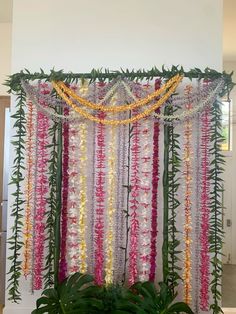 an arrangement of flowers and greenery is displayed on the wall