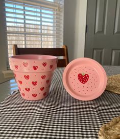 two pink cups sitting on top of a checkered table cloth