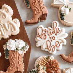 decorated cookies with cowboy boots and flowers are on a table next to a wooden cutting board