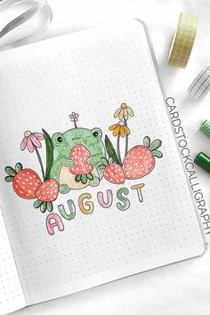 an open notebook with the word august written on it next to some markers and pens