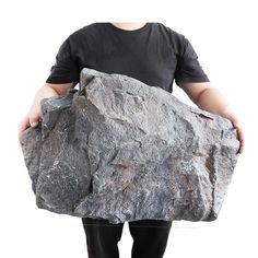 a man is holding a large rock in his hands while standing against a white background