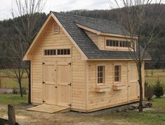 a small wooden shed with windows on the roof