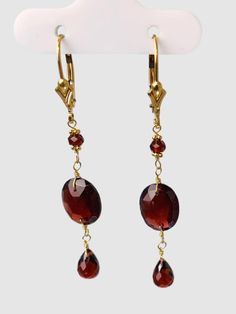 Garnet 3 station drop earring. each earring features a 10x12mm oval faceted checkerboard bead in the middle of a 3mm faceted round bead and 4x7mm briolette pear drop. Earrings are 14k yellow gold and 2.1" long. Metal - 14k Yellow Gold Gemstones - Garnet Length - 2.1" Elegant Earrings With Faceted Beads, Faceted Yellow Gold Oval Earrings, Yellow Gold Faceted Oval Earrings, Faceted Briolette Jewelry For Formal Occasions, Yellow Gold Faceted Briolette Earrings, Gold Oval Jewelry With Faceted Beads, 14k Gold Faceted Drop Earrings, Formal Teardrop Faceted Earrings, Elegant Oval Faceted Earrings