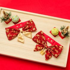 the wooden tray is decorated with red and gold bow ties, pine cones, and other decorations