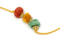 three different colored beads on a yellow cord