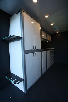 a kitchen with white cabinets and black flooring in the middle of an empty room