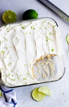 a pan filled with white frosting and limes next to sliced limes on the side