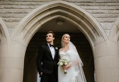 a bride and groom standing in front of an arch at the entrance to a church