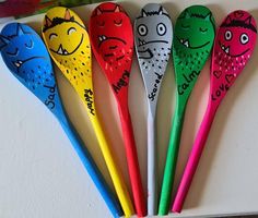 five colorful plastic spoons with cartoon faces on them are lined up in a row