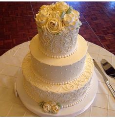 a three tiered wedding cake sitting on top of a table with utensils