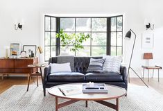 a living room with black leather couches and white rugs in front of large windows