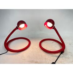 a pair of red lamps sitting on top of a white floor next to each other