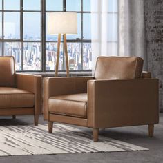 two brown leather chairs in front of a large window with a city view behind them