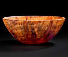 a wooden bowl sitting on top of a black table next to a white and red object