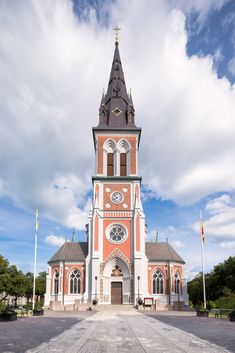 an old church with a clock tower and flags flying in the wind on a sunny day