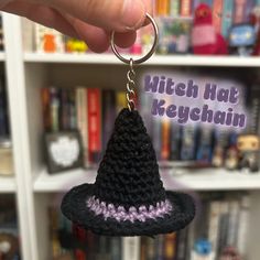 a crocheted witch hat keychain hanging from a book shelf