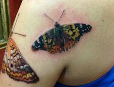 a close up of a butterfly on the back of a woman's shoulder and arm