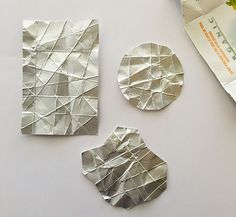 three pieces of silver foil sitting on top of a table