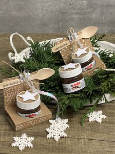 three jars of nutella sitting on top of a wooden table next to snowflakes