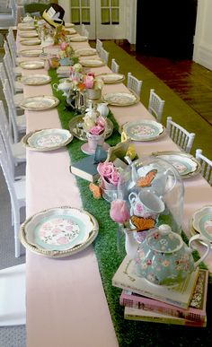 a long table set with plates and flowers on top of green carpeted flooring