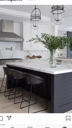 a large kitchen with white cabinets and marble counter tops, two stools at the island