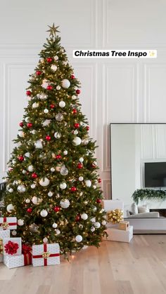 a decorated christmas tree in a living room with presents on the floor and a mirror behind it