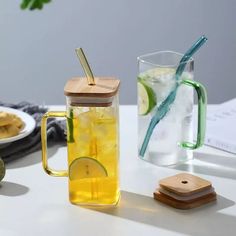 a glass pitcher filled with lemonade next to a plate of cookies and an apple