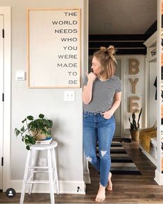 a woman standing in front of a sign that says the world needs who we were made to be