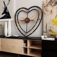 a heart shaped clock on top of a wooden cabinet in a room with paintings and vases