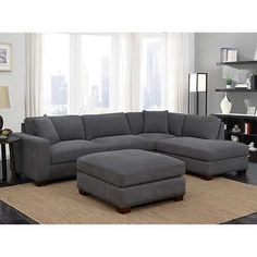 a living room with a large gray sectional couch and ottoman in front of a window