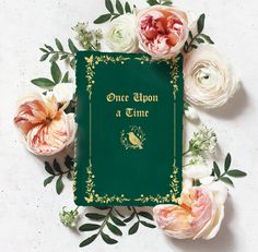 an open book surrounded by flowers on a white surface with the title once upon a time