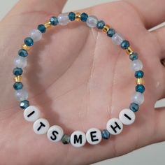 a hand holding a beaded bracelet that says it's meh