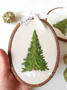 a hand embroidered christmas tree ornament on a wooden hoop with twine balls