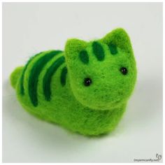 a close up of a small stuffed animal on a white surface with green stripes and black eyes