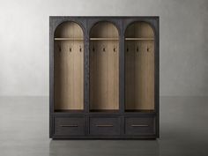 an open bookcase with three doors and drawers on the bottom shelf, in front of a gray wall