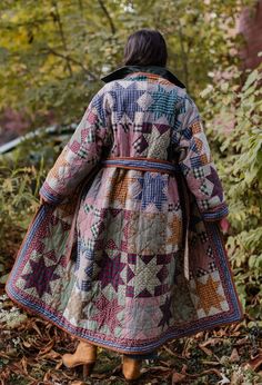 a woman is walking through the woods wearing a colorful coat