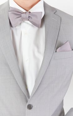 a man wearing a gray suit with a bow tie and pocket square in his lapel