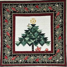 a quilted wall hanging with a christmas tree on it's side and birds around the tree