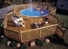 an above ground pool surrounded by wooden decking and fenced in area with people sitting around