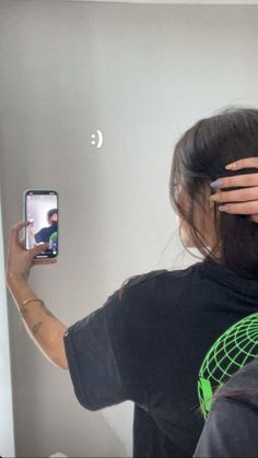 a woman is holding up her cell phone to take a selfie in the mirror