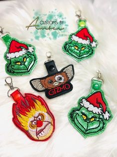 four christmas themed keychains with santa hats and grin face on them, all in different colors