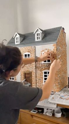 a woman is making a model house out of clay