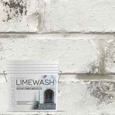 a white paint bucket sitting on top of a brick wall next to a cement planter