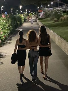 three women walking down a path at night with their backs turned to the camera,