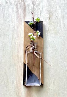 a bottle with some flowers in it hanging on a wall