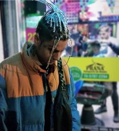 a man with dreadlocks talking on his cell phone in front of a store