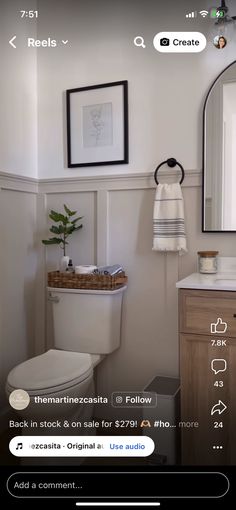 a white toilet sitting next to a wooden cabinet in a bathroom under a large mirror