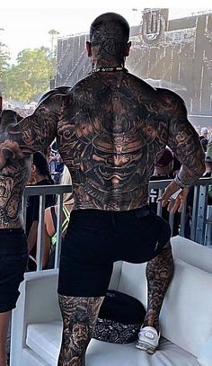 a man with lots of tattoos on his back standing next to a woman in black shorts