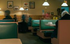 people sitting at tables in a restaurant with green booths